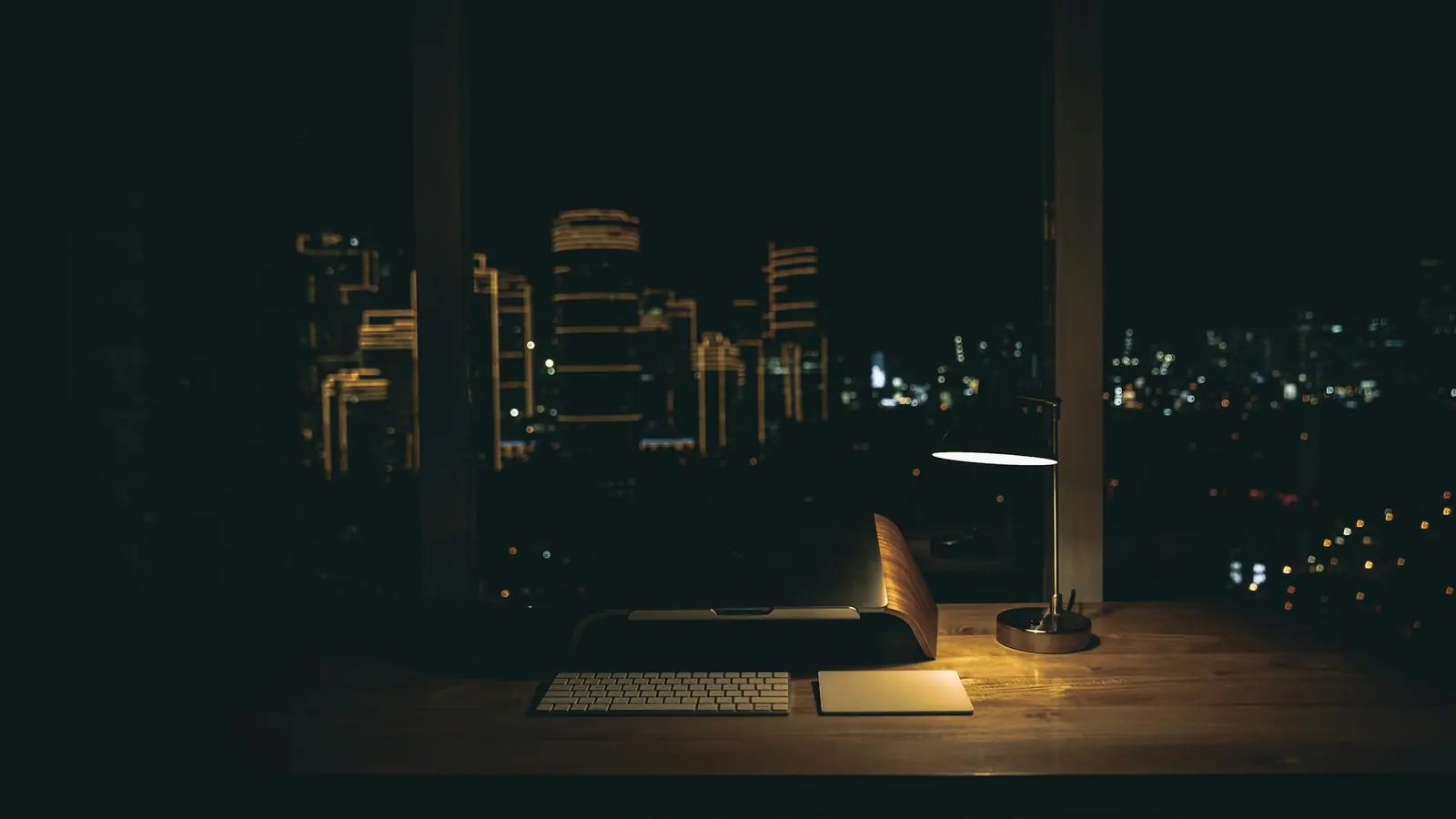 Two people's hands over an open laptop on a dark table, one pointing at the screen.